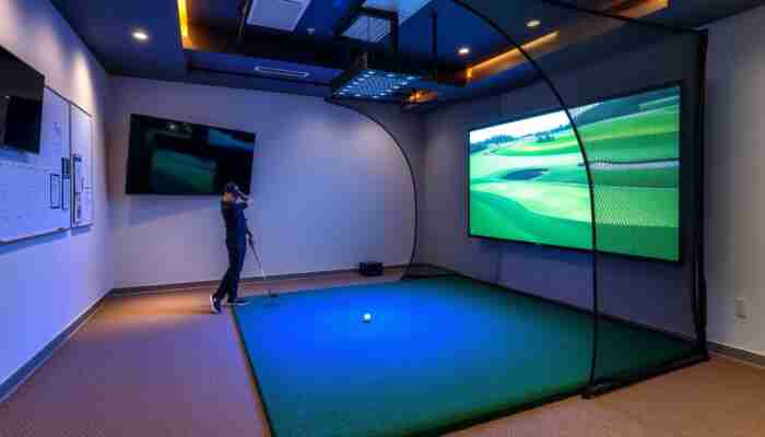Modern indoor golf simulator setup with a large display screen, high-tech simulator system, quality hitting mat, and protective impact net in a spacious area with golf decor and ambient lighting.