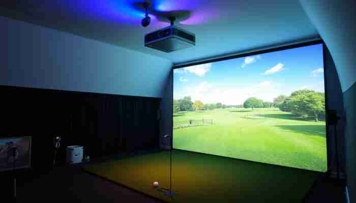 Ceiling-mounted golf simulator projector aligned with impact screen in an indoor golf room