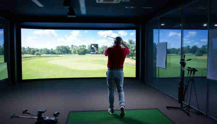 Golfer practicing on a high-tech simulator in an indoor setting, with a realistic golf course backdrop on a large screen, highlighting focus and determination.