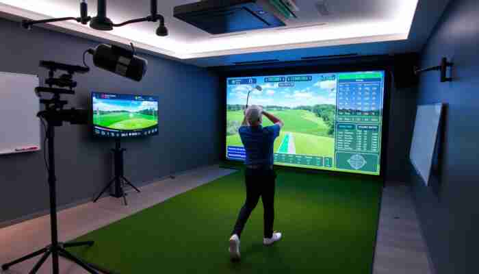 Commercial indoor golf simulator bay with launch monitor, impact screen and shot data display