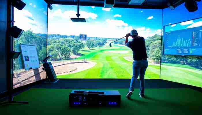 Golfer testing an indoor golf simulator and reviewing launch monitor data before purchase
