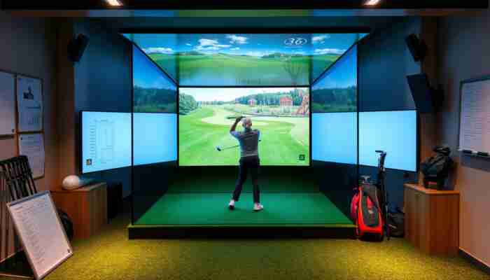 A golfer using a modern indoor golf simulator with a virtual course displayed on a screen in a cozy, well-lit room.